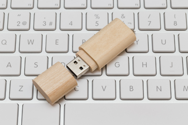 USB-Stick aus Holz auf weißer Tastatur USB-Stick aus Holz auf weisser Tastatur